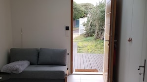 A modern room with a grey sofa, a small table, and a skylight leading to an outdoor area. - Contemporary villa -Exceptional view of the dune-Private pool (Soorts-Hossegor)