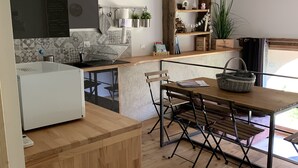 A modern kitchen with a wooden island, a dining area with a table and chairs, and a large window providing natural light. - Small independent apartment in farmhouse with air conditioning (Chavanod)