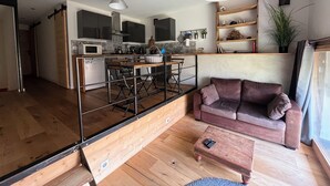 A modern kitchen with a dining area, a sofa, and a coffee table. - Small independent apartment in farmhouse with air conditioning (Chavanod)
