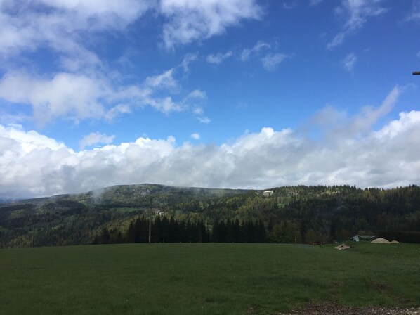 A wide, open field with a mountain range in the background and a partly cloudy sky. - Rent nature Studio (Prémanon)