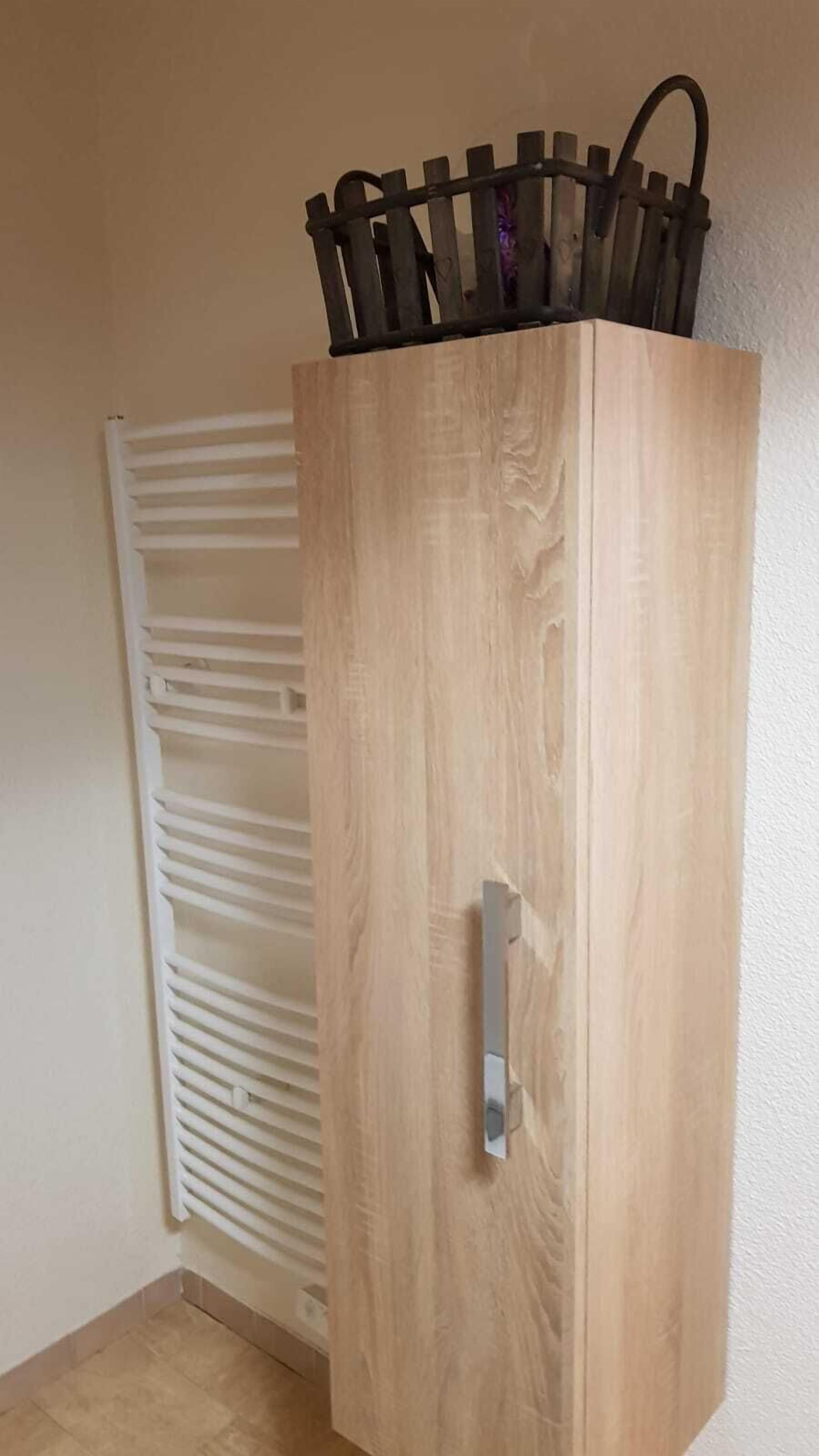 A wooden wardrobe with a handle and a metal rod on top.