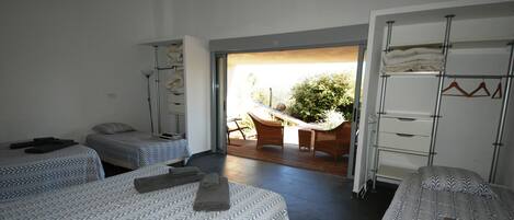 Habitación de hotel con tres camas, un balcón y vistas al exterior.