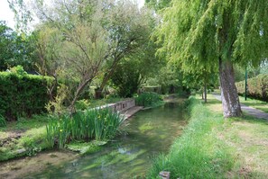 A serene garden with a narrow water channel, lush greenery, and a stone bridge. - F1-JARDINET privé CLOS - PARKING privé /MER à 300 Mètres Plages du Débarquement  (Asnelles)
