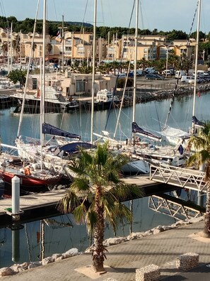 Una marina con barche ormeggiate, una palma sullo sfondo e edifici sullo sfondo.