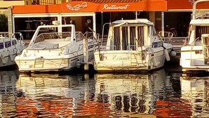 A marina with several boats docked, a restaurant with an orange awning, and buildings in the background. - Gruissan (Aude). Quiet apartment with marina view and parking space (Gruissan)