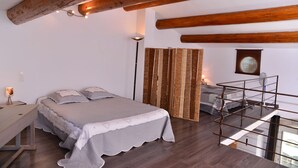 Ein Schlafzimmer mit Bett, Nachttisch, Lampe und Blick auf einen Balkon.