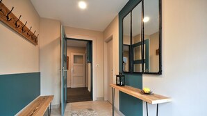 A hallway with a wooden bench, a small table with a lantern, and a mirror on the wall. - Parenthèse Vin - Large house with terrace for 12 people in Eguisheim (Eguisheim)