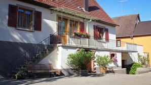A two-story house with a balcony, a wooden bench, and potted plants. - Parenthèse Vin - Large house with terrace for 12 people in Eguisheim (Eguisheim)
