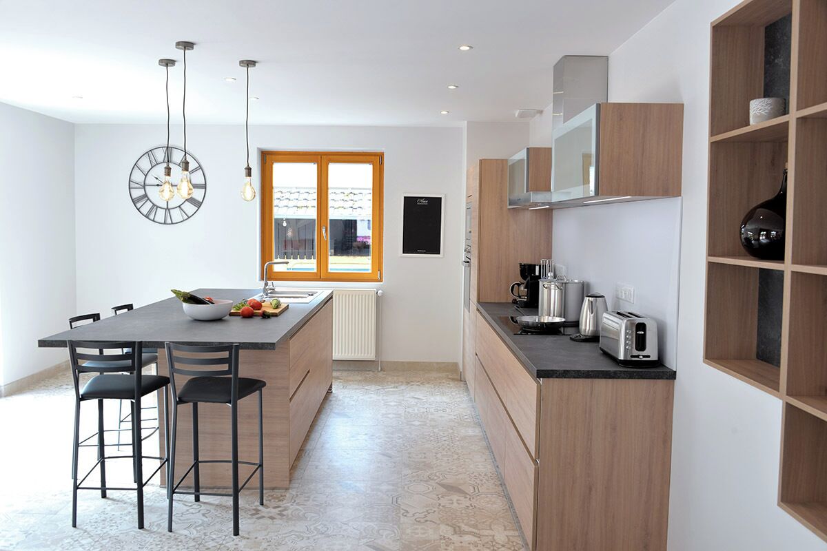A modern kitchen with a central island, bar stools, a built-in oven, and a microwave.