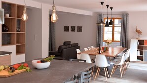 A modern dining area with a long table, white chairs, and a bowl of fruit on the counter. - Parenthèse Vin - Large house with terrace for 12 people in Eguisheim (Eguisheim)