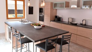 A modern kitchen with a central island, stainless steel appliances, and pendant lighting. - Parenthèse Vin - Large house with terrace for 12 people in Eguisheim (Eguisheim)