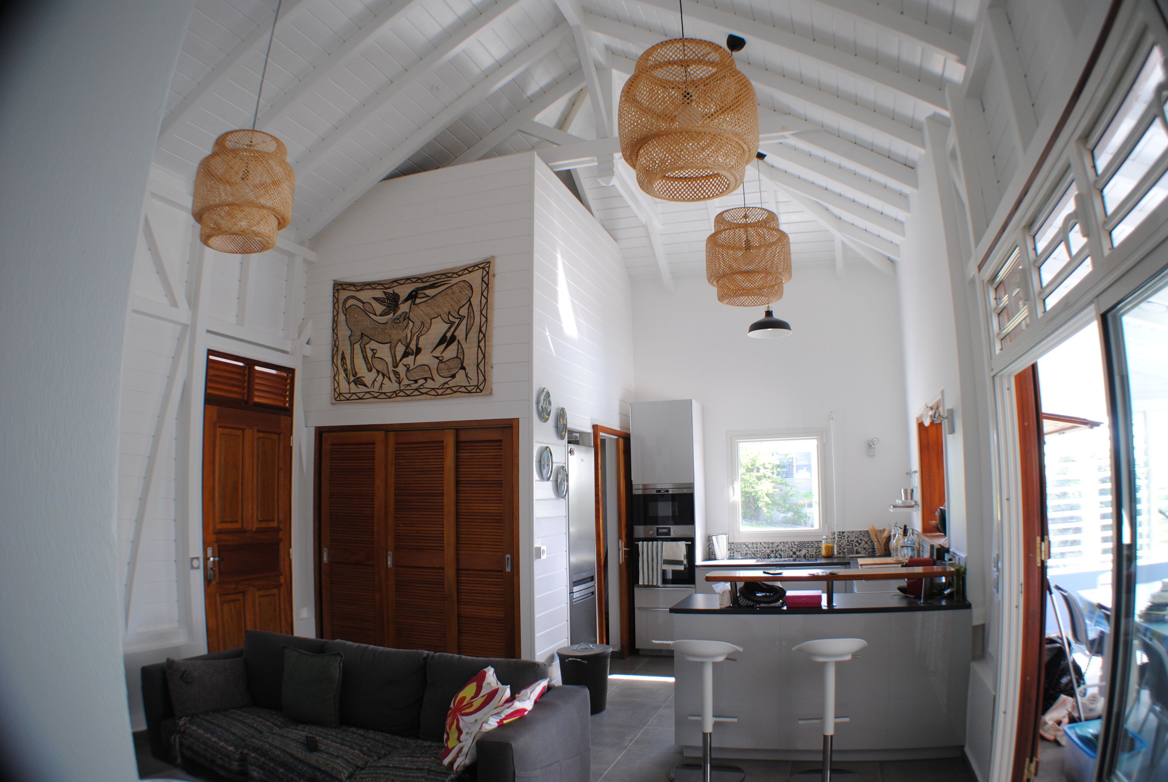 A spacious living area with a sofa, a kitchen with a bar, and a dining area.