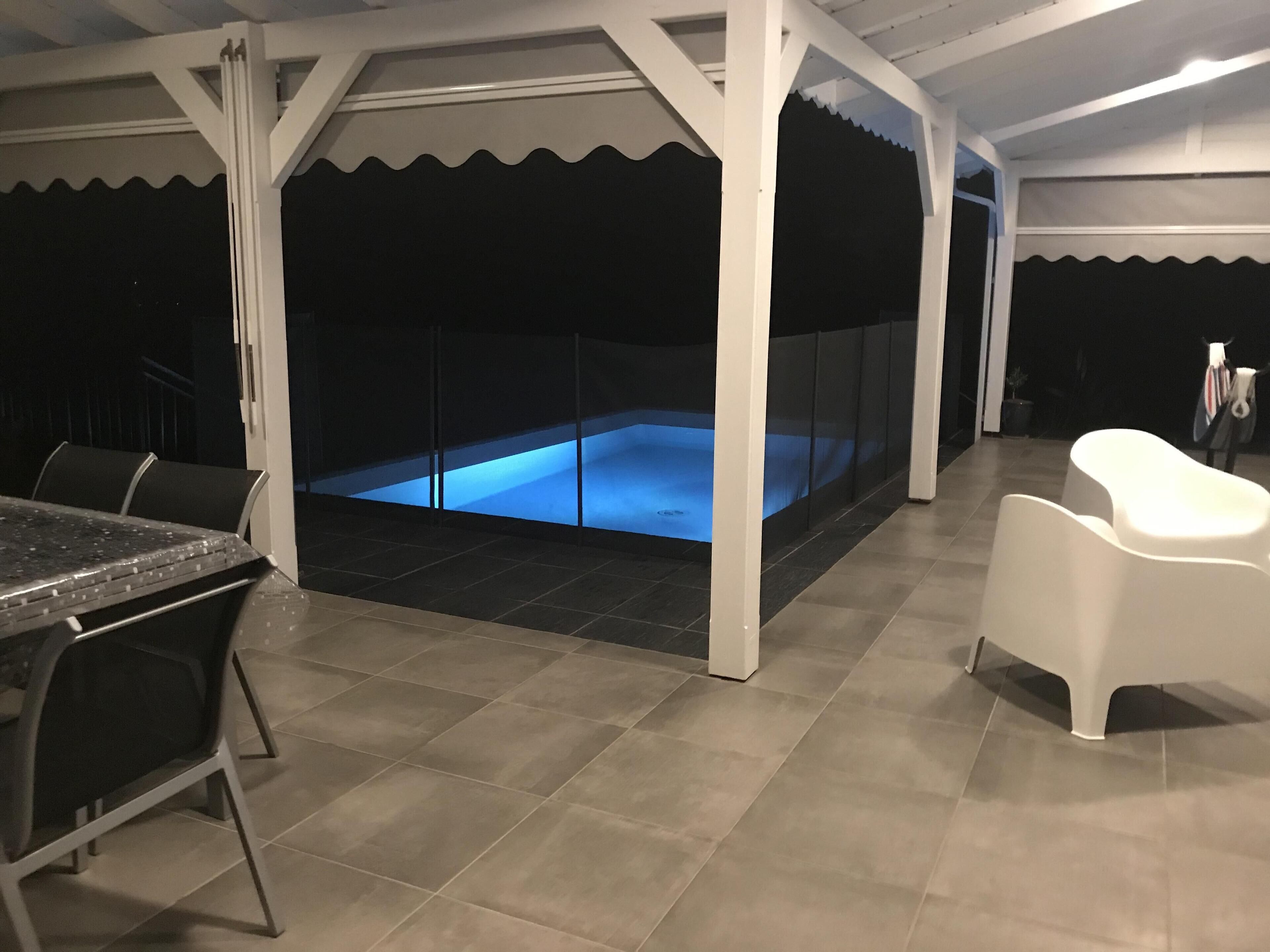 An outdoor hot tub area with a covered seating area, a table, and chairs.