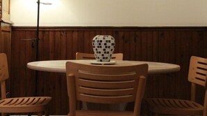 Ein Essbereich mit einem runden Tisch, vier Holzstühlen, einer Lampe und einem gerahmten Bild an der Wand.