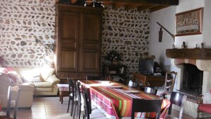 Un espace repas comprenant une longue table, des chaises, un canapé et un mur en pierre.