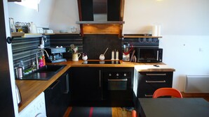 A compact kitchen with a coffee machine, microwave, and oven. - Superb comfortable apartment with sea view (Perros-Guirec)