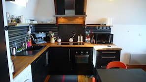 A compact kitchen with a coffee machine, microwave, and oven. - Superb comfortable apartment with sea view (Perros-Guirec)