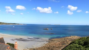 A coastal view with a sandy beach, clear blue sea, and houses with sloped roofs. - Superb comfortable apartment with sea view (Perros-Guirec)