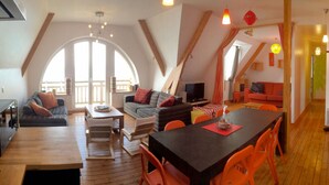 A cozy loft-style living space with a dining area, a kitchen, and a balcony with a view. - Superb comfortable apartment with sea view (Perros-Guirec)