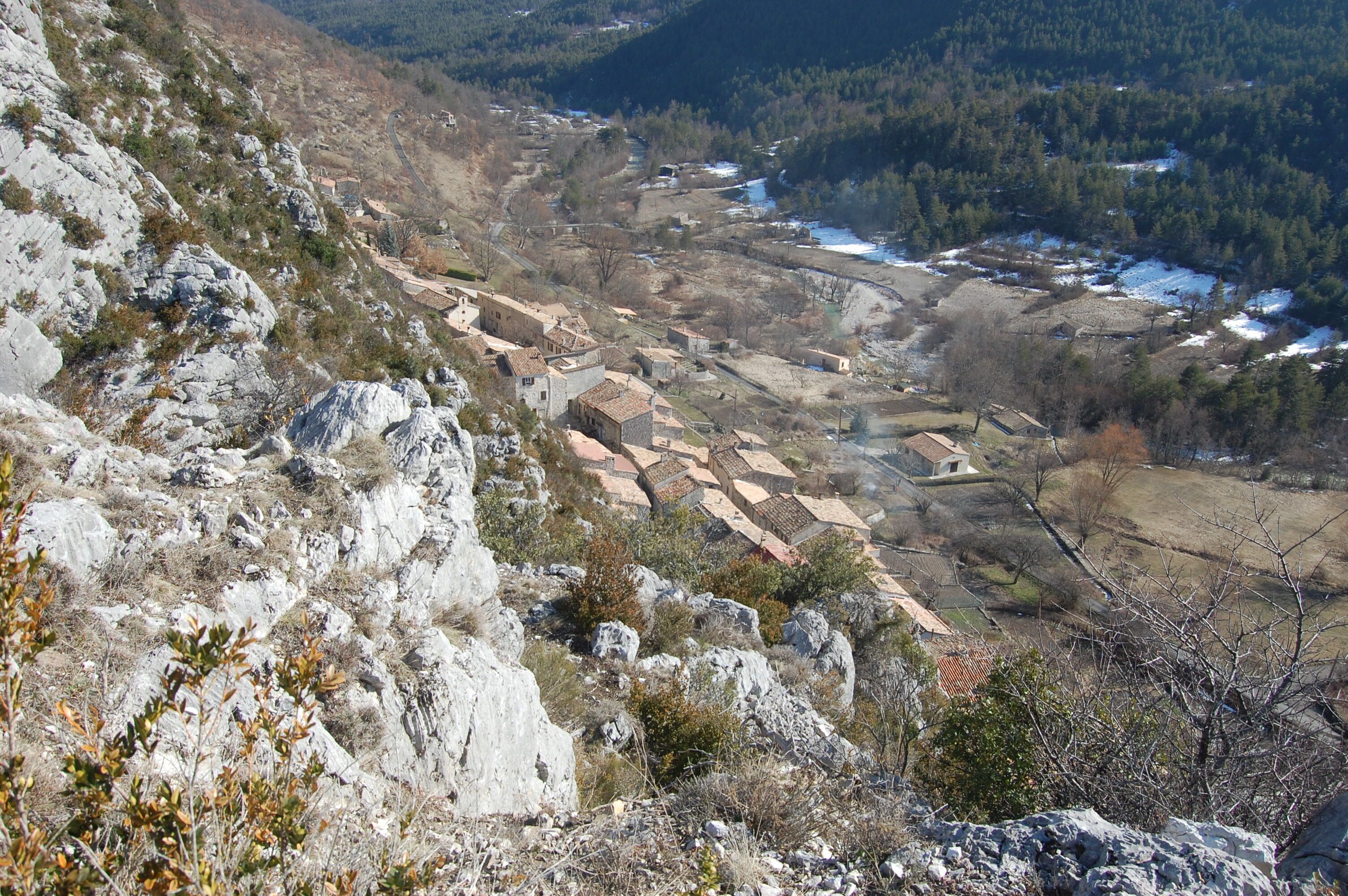 Eine gebirgige Landschaft mit einem Tal darunter, mit einer Serpentinenstraße und verstreuten Gebäuden.