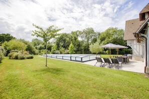 A patio area with a glass enclosure, outdoor seating, and a view of the surrounding greenery.