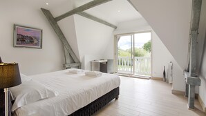 Un dormitorio con una cama grande, un escritorio y un balcón con vistas.