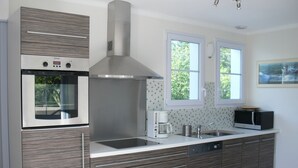 Una cocina moderna con horno empotrado, campana extractora de acero inoxidable, pileta doble y microondas.