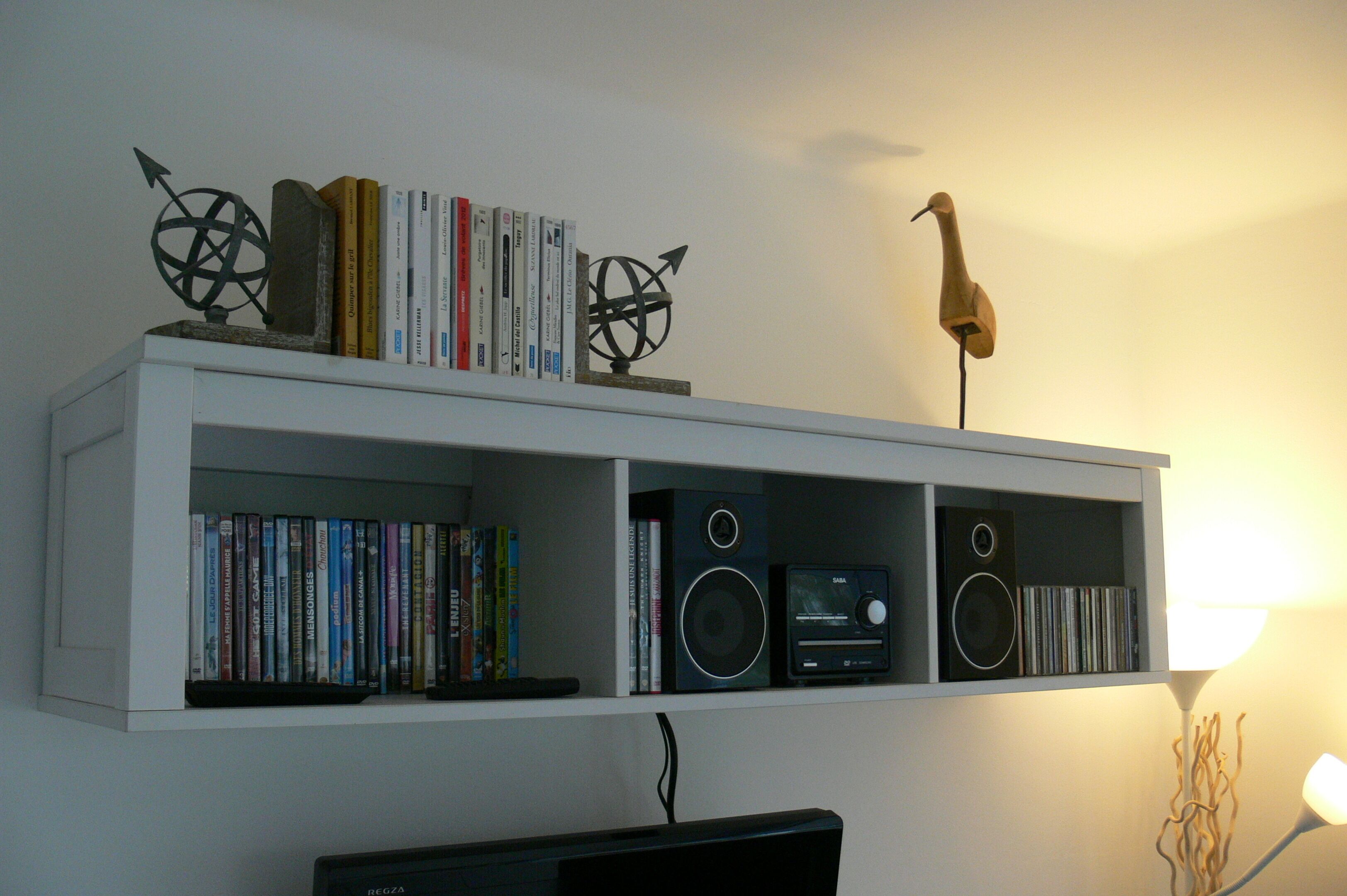 A bookshelf with books and decorative items, a speaker, and a lamp.