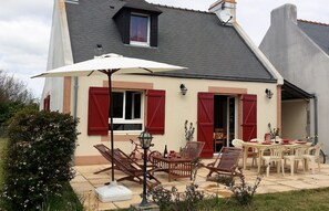 Une maison dotée d’un patio aménagé avec du mobilier d’extérieur, une antenne parabolique et un vélo.