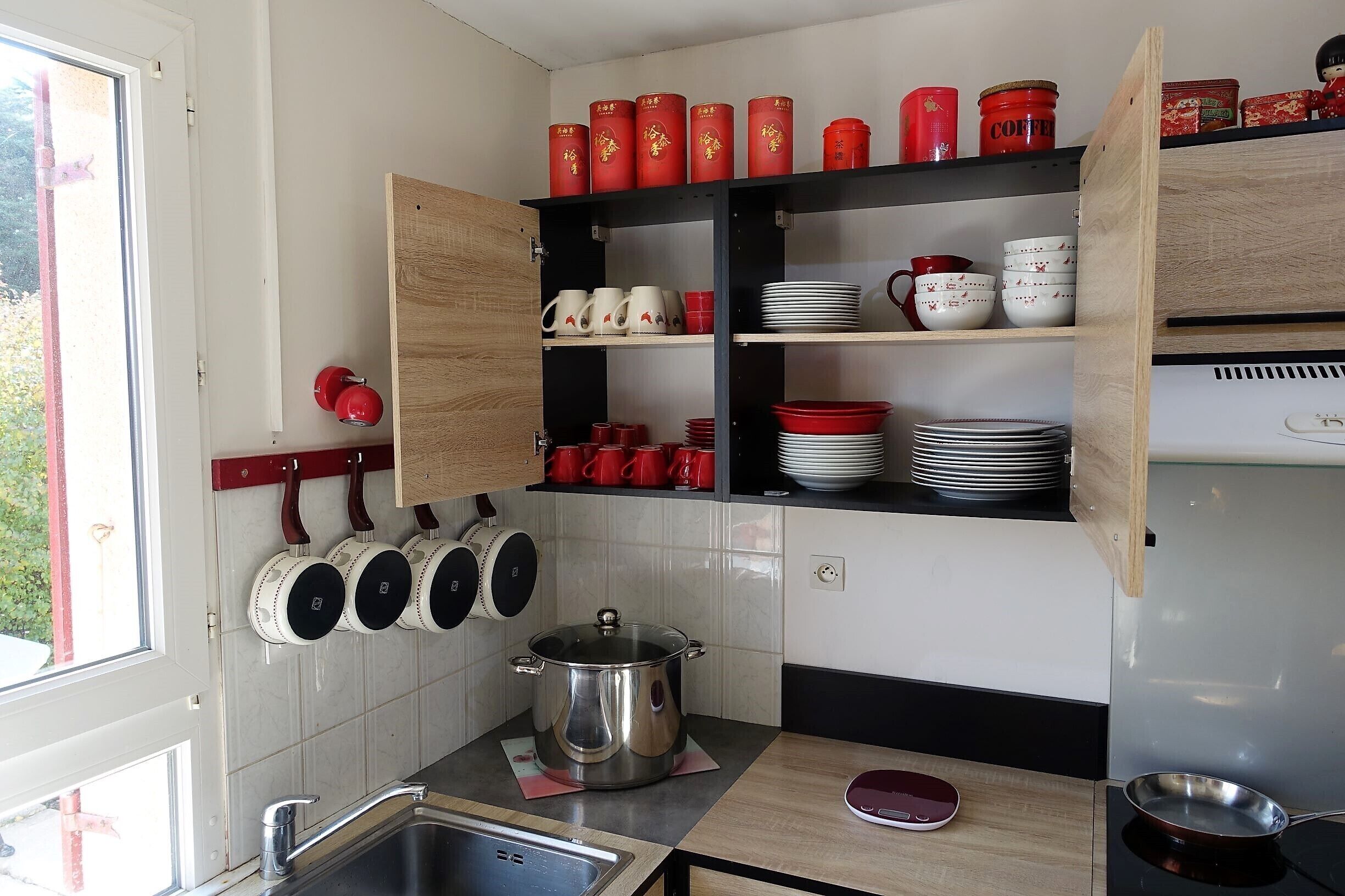 Une cuisine avec un meuble en bois, une casserole sur le plan de travail et divers ustensiles de cuisine.