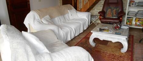 Una sala de estar con un sofá, una mesa de centro, un sillón rojo y una estantería.