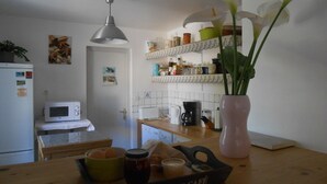 Eine Küche mit Mikrowelle, Toaster und Kaffeemaschine auf der Arbeitsplatte. Auf der Arbeitsplatte steht eine Vase mit weißen Blumen.