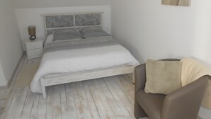 Ein Schlafzimmer mit einem Bett, einem Nachttisch, einem Sessel und einem Wandbild.