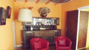 A room with a wooden cabinet, two red chairs, a lamp, and a door. - House downtown, PORT DE PLAISANCE d'AUDIERNE, wifi (Audierne)