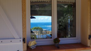 A sliding glass door with a view of the ocean and patio furniture. - villa marina , climatised,wi-fi, private garden and parking. (Sartène)