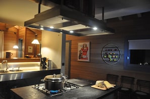 A modern kitchen with a gas stove, a coffee machine, and a fruit display.