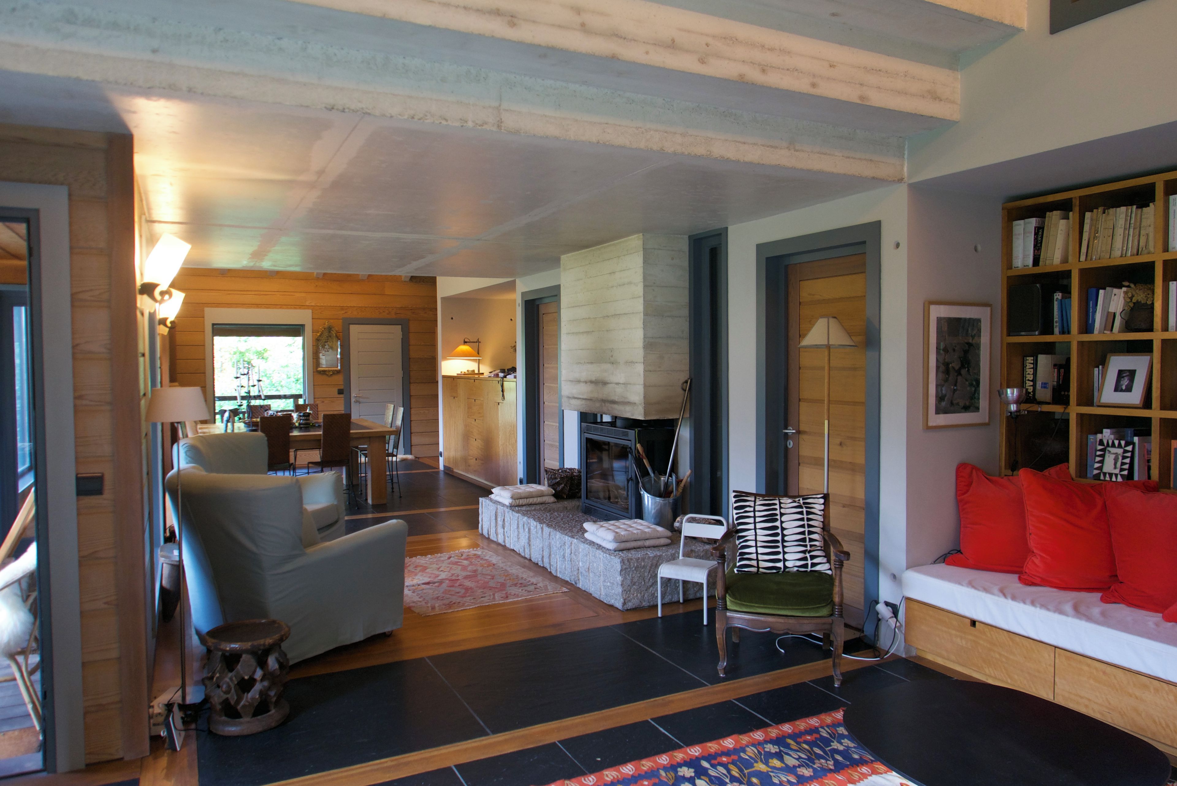 Een ruime woonkamer met een open haard, een bank, een eethoek en een boekenkast.