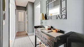 A hallway with a dark wooden console table, a lamp, and a mirror with geometric patterns. - Cosy and spacious 145m² family apartment (Paris)