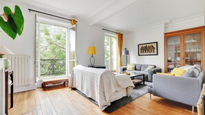 Ein geräumiges Wohnzimmer mit großem Fenster, einer Couch, einer Bank und einem Schrank.