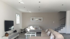 A modern living room with a sofa, coffee table, TV, and artwork on the wall.