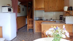 A kitchen with wooden cabinets, a microwave, a refrigerator, and a sink.