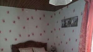 Une chambre avec un lit en bois, un papier peint à motifs floraux et un plancher en bois.