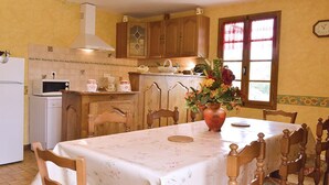 Une cuisine avec des meubles de rangement en bois, un réfrigérateur blanc, un four à micro-ondes et une table à manger avec des chaises.