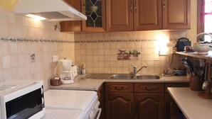 Une cuisine avec des meubles de rangement en bois, un four à micro-ondes, une cuisinière et un évier.