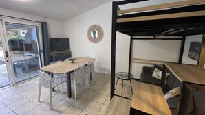 A compact living space with a dining table, chairs, a TV, and a bunk bed. - 100 metres from Santa Guilia beach, comfortable, garden furniture, barbecue (Porto-Vecchio)