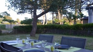 An outdoor dining table set with plates, cutlery, and glasses, surrounded by chairs and greenery. - Bungalow, enclosed garden, direct beach access (La Turballe)