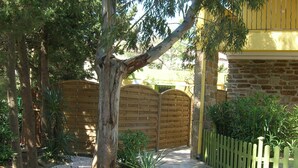 Un jardín con un sendero de grava, cerca de madera y pared de piedra.