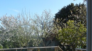 Un patio al aire libre con una terraza de madera, una mesa blanca y dos sillas blancas.