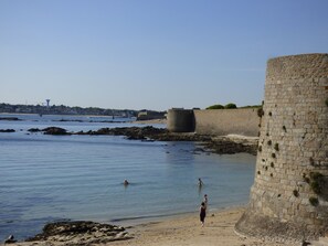 Explore the historic stone fortification, situated beside a serene beach with calm waters.