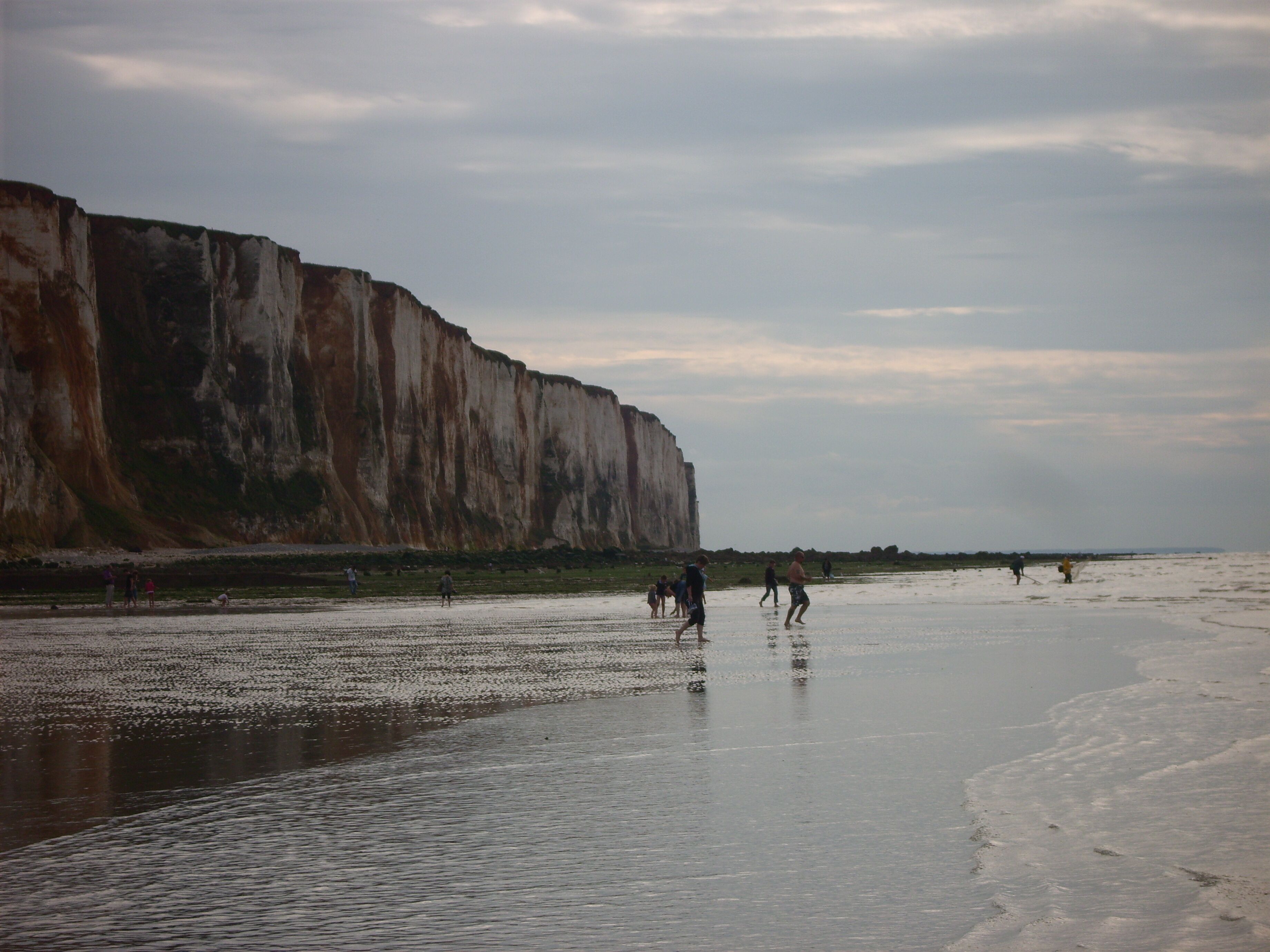 A beach with a large cliff in the background.